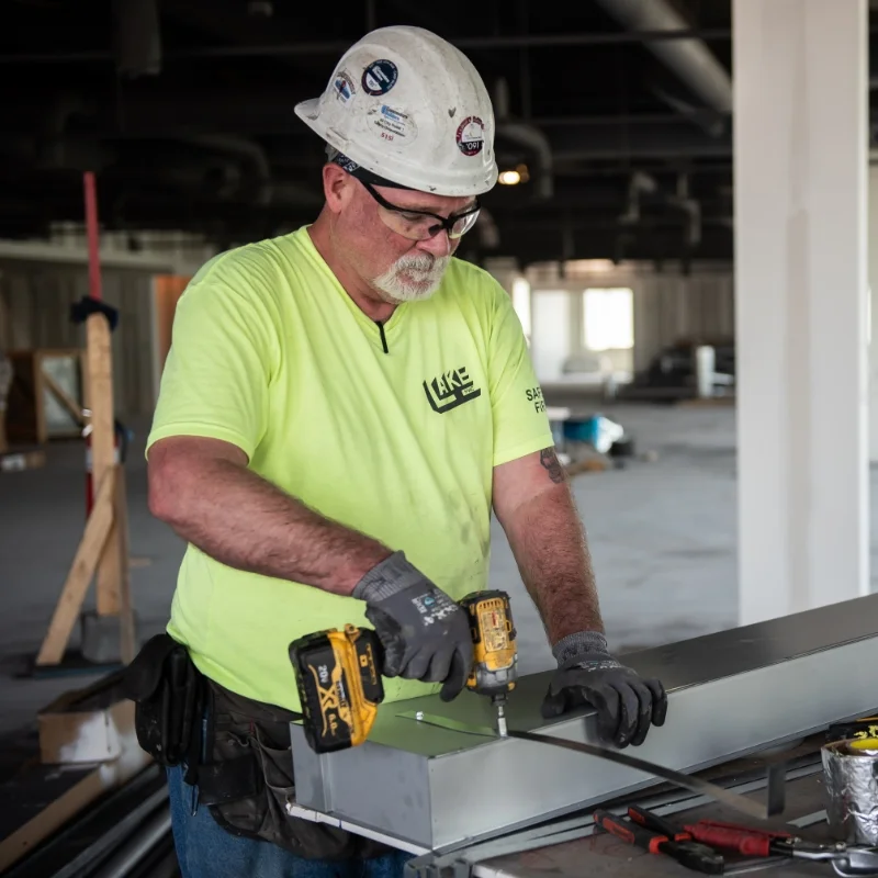 Integrated Builders construction worker in safety gear drilling holes